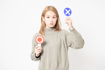 白い背景の前に立ってOKとNGのプラカードを見せている若い女性