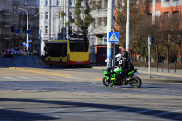 Motocyklista z pasażerem jedzie ulicą Wrocławia.	
