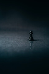black pawn on a dark, black background, reflection, chess piece