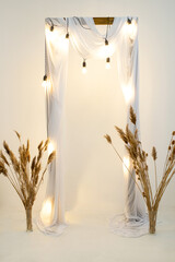 wooden wedding arch in the studio with a garland of lamps