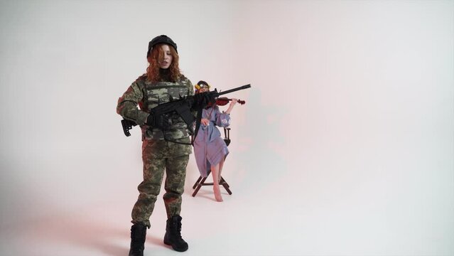Woman warrior with assault rifle and woman musician with violin in studio. Concept of war in Ukraine