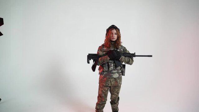 Ukrainian young woman soldier in camouflage uniform and assault rifle and helmet.Ukraine war concept