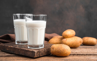 Potato milk in two glasses on a brown background. Vegetarian milk. Side view, horizontal.