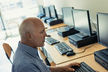 middle-aged man uses a desktop PC workstation in a common room