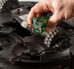 the serviceman changes the faulty battery in the robot vacuum cleaner.