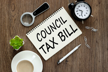 COUNCIL TAX BILL text on an open notebook near a green plant and a cup of coffee