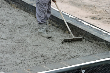 A builder levelling and spreading concrete with a rake