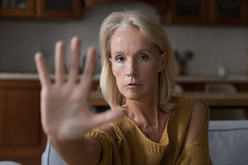 Worried mature Caucasian lady making hand stop gesture, saying no violence, abuse, aggression, showing palm, expressing protest, refusal, fighting against age discrimination, force. Close up