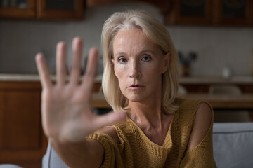 Worried mature Caucasian lady making hand stop gesture, saying no violence, abuse, aggression,...