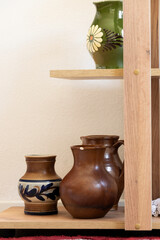 Different ceramic pottery vases on shelves, interior design