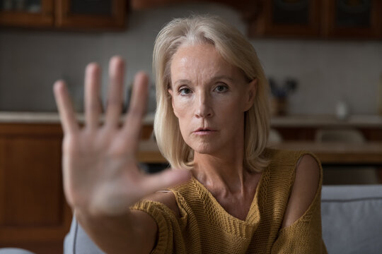 Worried mature Caucasian lady making hand stop gesture, saying no violence, abuse, aggression, showing palm, expressing protest, refusal, fighting against age discrimination, force. Close up