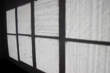 Light and shadow of a old window frame on a white grungy wall