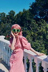 cheerful woman in green glasses pink dress posing outdoors