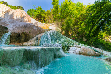 Geothermal pool and hot spring in Tuscany, Italy. Bagni San Filippo natural thermal waterfall in the morning with no people. The White Whale amidst forest.