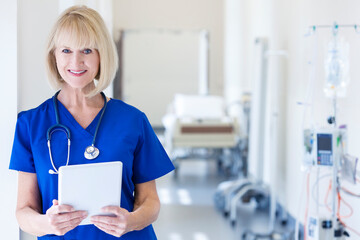 Portrait of Caucasian female nurse using tablet technology in hospital corridor
