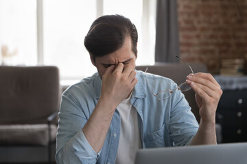 Frustrated tired freelance employee overworking at laptop computer in home office, feeling...