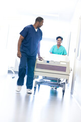 African American nursing staff in scrubs with hospital bed in healthcare centre