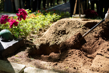 Burying grave. Funeral details. Mourning ceremony. Gravedigger with shovel.