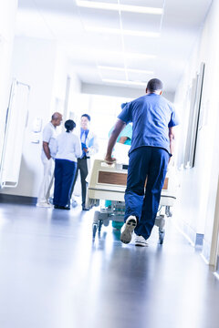 Multi ethnic medical staff with patient in corridor modern healthcare facility