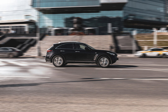 Car Infiniti QX70 SUV is driving on urban speedway with city buildings background