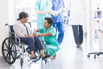 African American patient and nurse with medical staff in hospital corridor