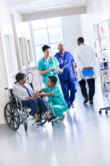 African American patient and nurse with medical staff in hospital corridor