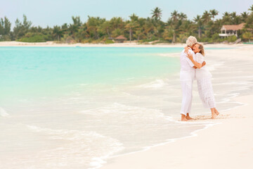 Fototapeta na wymiar Happy mature Caucasian couple walking outdoors together on tropical beach
