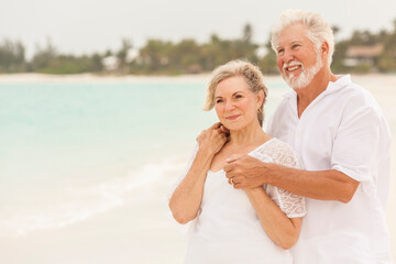 Fototapeta na wymiar Retired Caucasian senior couple in white clothes on a travel resort beach