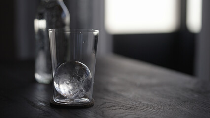 tonic water with ice ball in tumbler glass on wood table