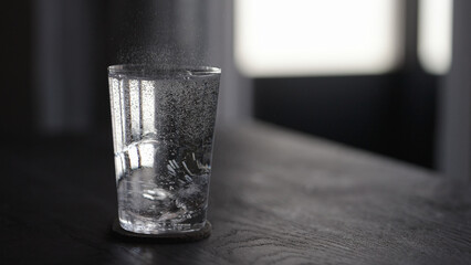 tonic water with ice ball in tumbler glass on wood table