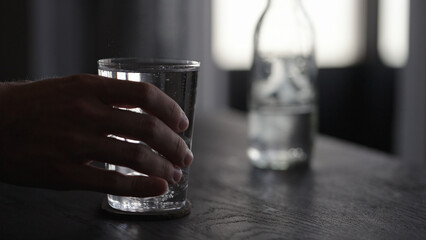 man hand take tonic water with ice ball in tumbler glass on wood table