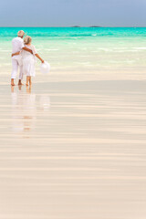 Attractive senior Caucasian couple in white living an island lifestyle on beach