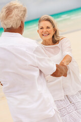 Fototapeta premium Happy mature Caucasian couple in white dancing beside ocean on tropical beach