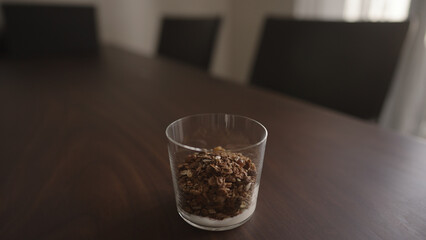 making granola with yogurt in tumbler glass on wood table