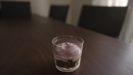 making granola with yogurt in tumbler glass on wood table