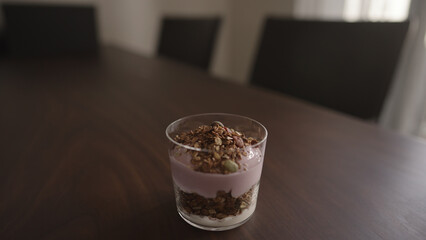 making granola with yogurt in tumbler glass on wood table