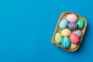 Multi colors Easter eggs in the woven basket on colored background . Pastel color Easter eggs. holiday concept with copy space