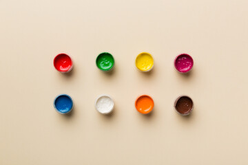 jars with gouache of different colors on Colored background. hobby painting. Top view with empty space. workplace for creativity. home teaching concept drawing