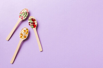 Vitamin capsules in a wooden spoon on a colored background. Pills served as a healthy meal. Drugs, pharmacy, medicine or medical healthycare concept