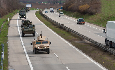 Army military convoy passes  in Czech Republic. Wheeled armored vehicles drive on highway . - obrazy, fototapety, plakaty