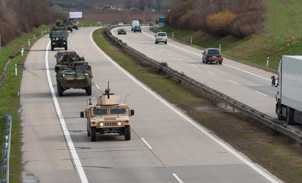 Army military convoy passes  in Czech Republic. Wheeled armored vehicles drive on highway .