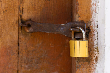 Padlock on an old brown wooden door with cracked paint. Close-up
