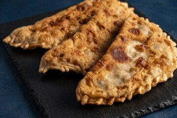 Homemade fried chebureks on a black stone. Azerbaijani, Tatar, Caucasian, Greek cuisine.