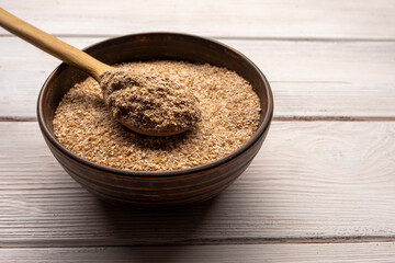 Wheat bran in bowl on a white wooden table.