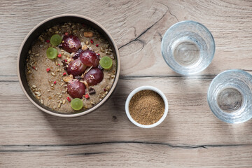 Bowl of flaxseed porridge with grapes on a brown wooden table, flat lay, horizontal shot