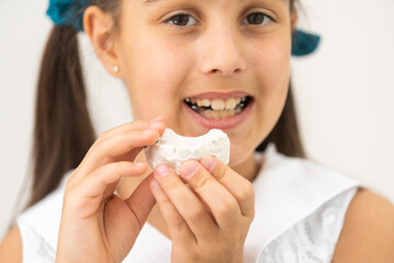 Teenager is holding a dental cast model at the start of orthodontic treatment alongside her teeth after the treatment was completed.