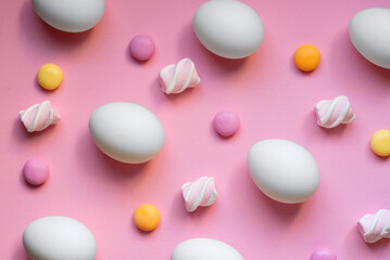 Pattern with eggs, candies, and marshmallows on pink background. Easter holiday concept. 