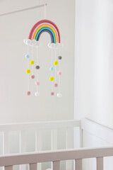 white crib with colorful rainbow mobile in nursery room	 - 496604716