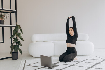 A sporty woman in sportswear using a laptop at home in the living room. Sport and recreation concept.