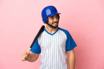 Baseball player with helmet and bat isolated on pink background looking to the side and smiling